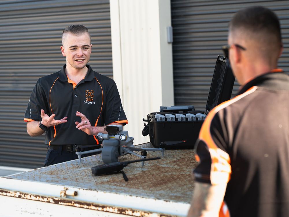 Zak briefing a client over the drone and controller on a ute tray